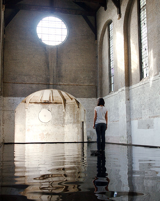 Bridge at Dilston Grove. A woman stands in the middle of a pool of water completely cut off from shore.
